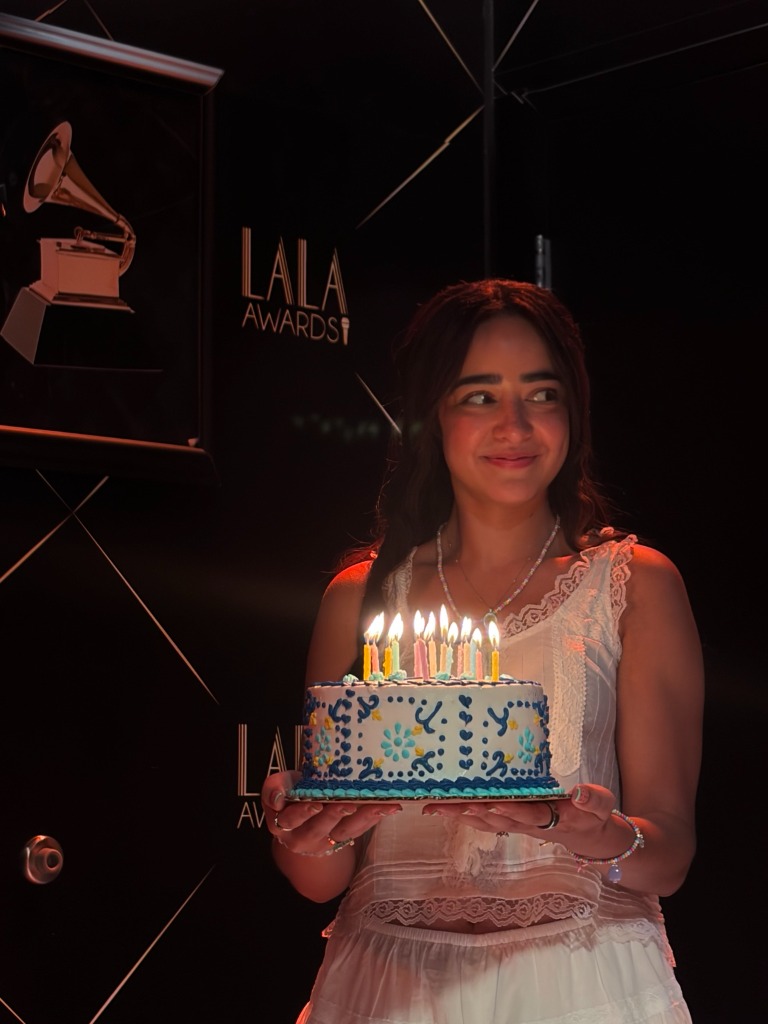 The creator smiling while holding a birthday cake at an event